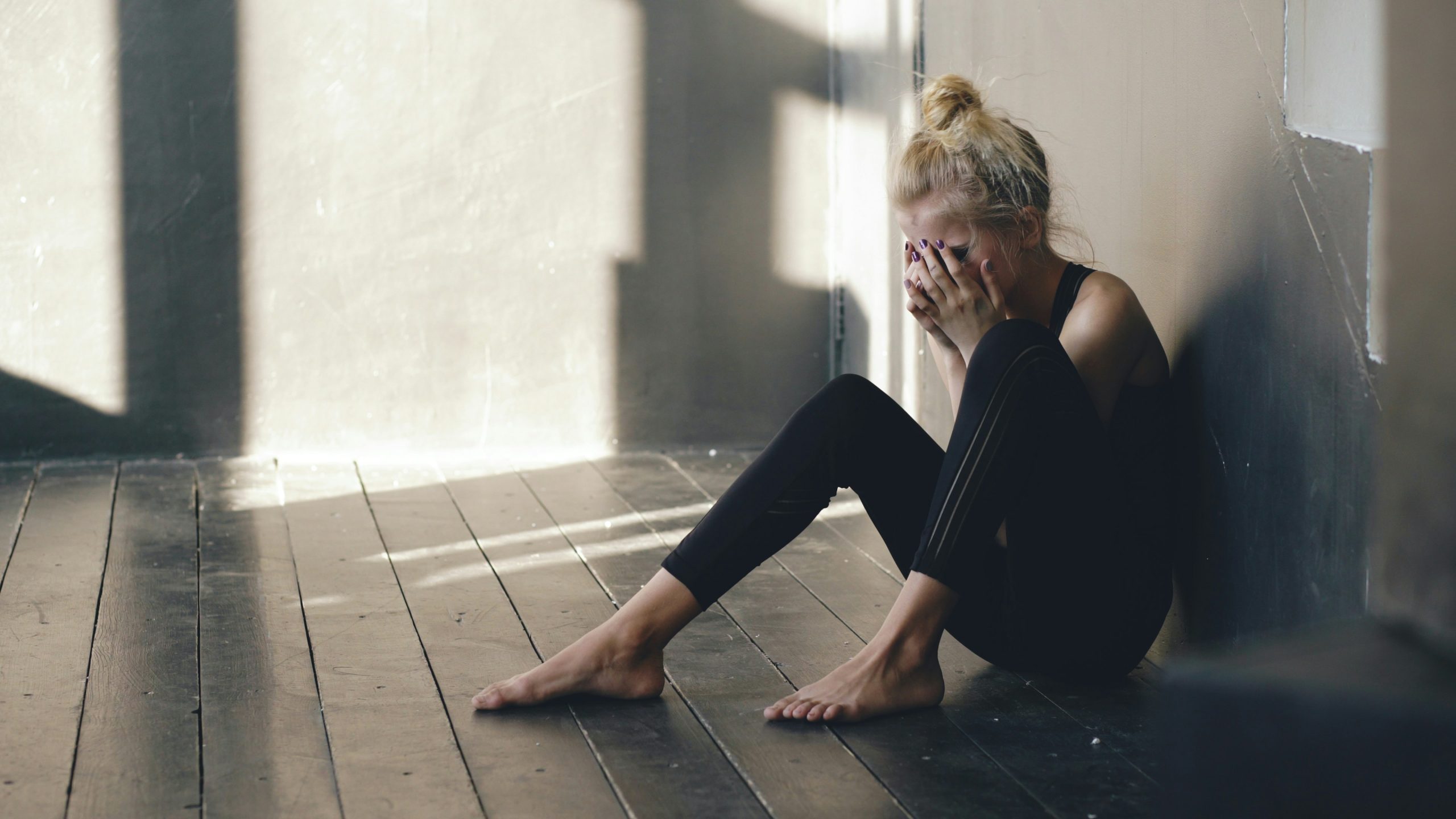 woman sitting alone on the floor covering her face representing anxious attachment after a breakup