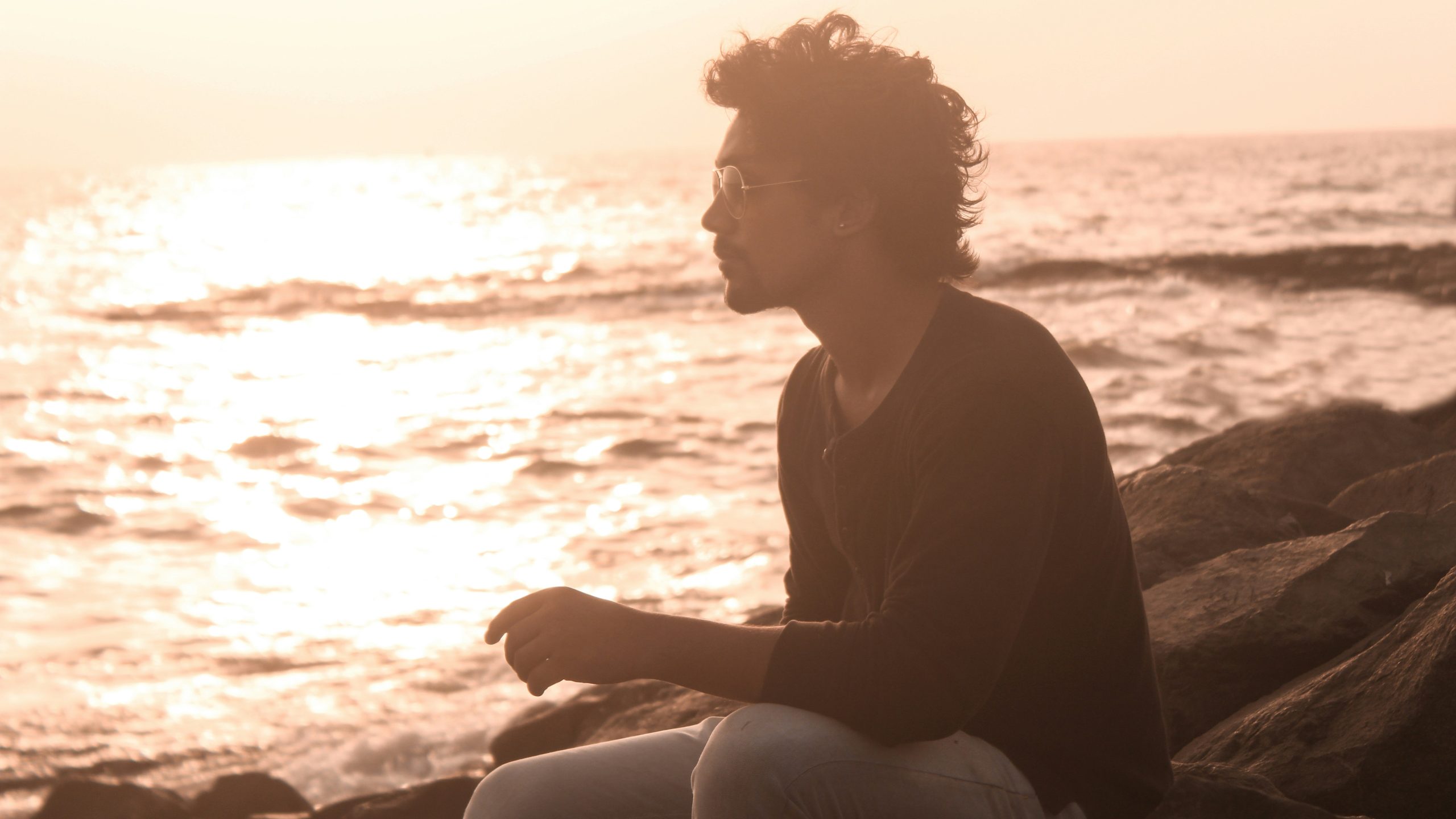 man sitting alone on rocks at sunset reflecting on self-worth and anxious attachment