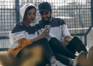 Couple sitting together looking at a relationship app on their phone