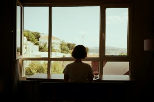 Woman alone at window reflecting on love bombing and anxious attachment patterns